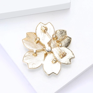Detail showing the golden flower brooch back with safe pin clasp and brushed alloy texture