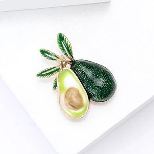 Broche avocat en émail avec texture réaliste et feuilles vertes sur un support blanc pur
