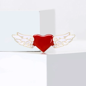 Broche cœur en émail rouge avec ailes dorées sur un fond blanc au design minimaliste