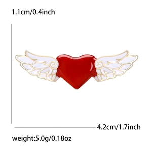 Broche cœur en émail rouge avec ailes d'ange blanches et bordure dorée sur fond blanc