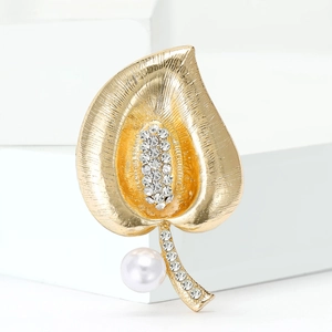 Macro view of gold leaf brooch with brushed metal texture and sparkling rhinestone details