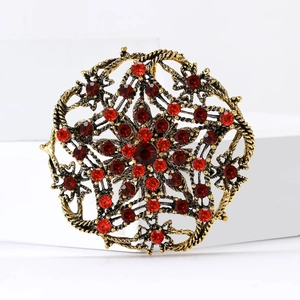 Vintage gold starburst brooch with red rhinestones and centered crimson gemstone
