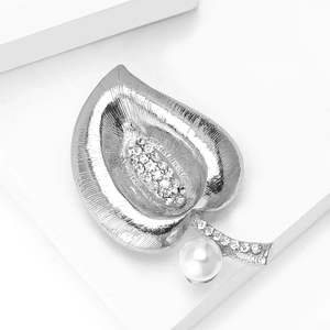 Detailed view of silver leaf brooch with sparkling crystals and a white pearl accent