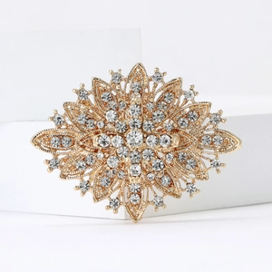 Vintage gold starburst brooch with sparkling rhinestones on a white display stand