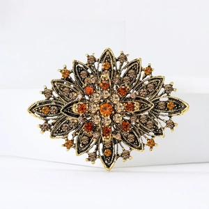 Macro shot of luxury vintage gold brooch featuring amber rhinestones and floral details