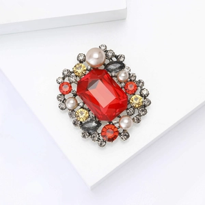 Gros plan détaillé d'une broche vintage avec un grand cristal rouge et des perles
