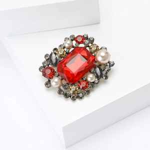 Détails d'une broche vintage de luxe avec cristal rouge et perles d'imitation blanches