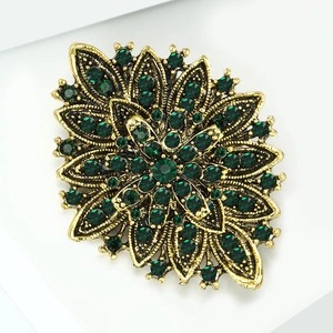 Macro shot of vintage gold sunflower brooch with emerald green crystal embellishments