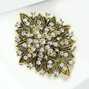Macro shot of vintage gold flower brooch with layered petals and inlaid rhinestones