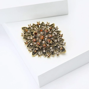 Macro detail of luxury vintage gold sunflower brooch with amber rhinestones and crystals