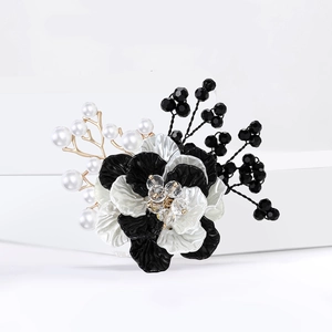 Detalle de broche de flor tejida con cristal central, perlas y ramas doradas chic