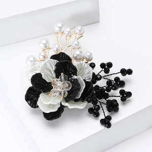 Detalle del broche de flor tejida con perlas, cuentas negras y ramas doradas