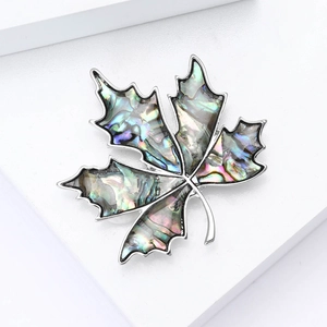 Elegant maple leaf brooch with colorful shell inlay and silver metal finish on white stand