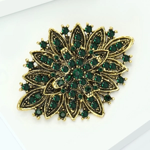 Detailed macro view of vintage flower brooch featuring dark green rhinestones and gold metal