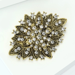Close-up of vintage flower brooch featuring antique gold metal and sparkling rhinestones