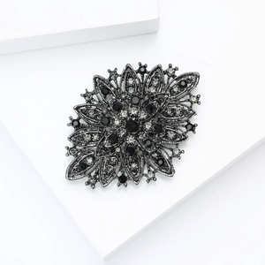 Macro detail of retro floral badge brooch with black alloy and crystal rhinestones