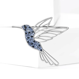 Exquisite hummingbird brooch with blue crystals and silver wings on white display stand