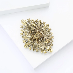 Macro detail of vintage gold badge brooch showing back safety pin and metal plating texture
