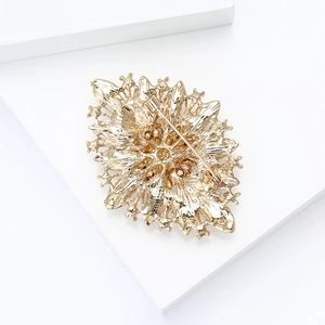 Detail view of the golden alloy brooch showing the back needle closure and metal texture