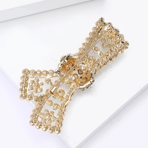 Detail view of gold alloy vintage brooch with hollow pattern and secure safety pin closure