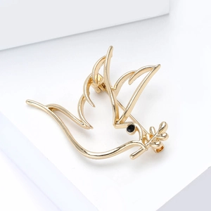 Élégante broche oiseau doré avec branche d'olivier en métal poli sur socle blanc