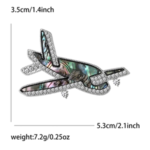 Broche avion raffinée avec ailes en nacre irisées et strass brillants sertis dessus