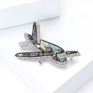 Élégante broche avion argentée avec incrustation de nacre et strass scintillants