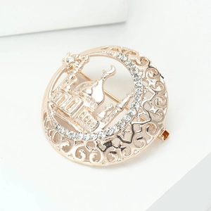 Close-up of gold mosque brooch with crescent moon and white rhinestones detail