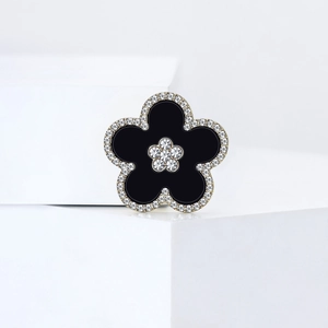 Detailed macro view of black floral brooch with sparkling rhinestones on white block