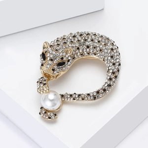 Detail van de fonkelende stras-luipaardbroche met een ronde witte parel op goudkleurige legering