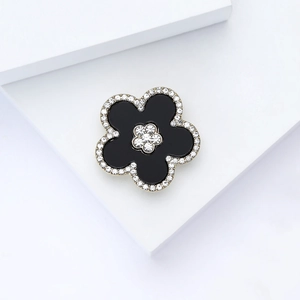 Macro shot of an elegant black enamel flower brooch with sparkling rhinestones on petals