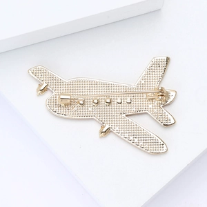 Detailed back view of golden airplane brooch showing pin clasp and textured metal surface