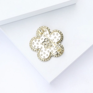 Macro detail of gold flower brooch back featuring intricate floral texture and safety pin