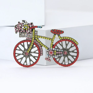 Vintage silver bicycle brooch with colorful crystals on a white minimalist pedestal