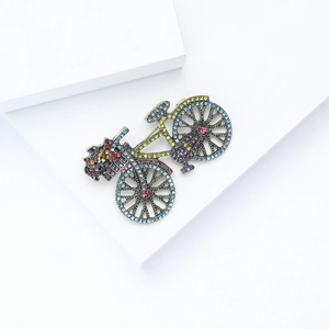 Detailed close-up of retro bicycle brooch with colorful crystals on golden frame