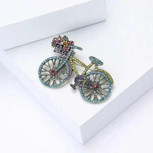 Detailed close-up of retro bicycle brooch with multi-colored crystals on a white platform