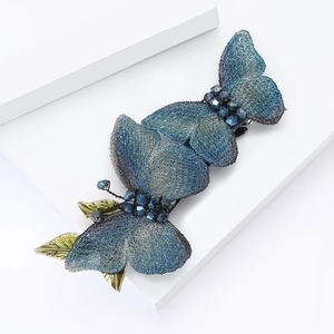Elegant blue fabric butterfly hair clip with green metal leaf accents and beaded details