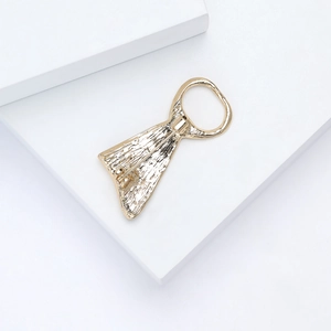 Detail shot of golden metal brooch with textured finish on a white geometric stand