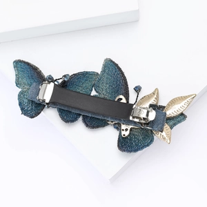 Detailed macro shot of an elegant blue fabric butterfly hair clip with golden leaf and beads