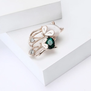 Elegant rose gold cat brooch with green gemstone and opal-like stone on white pedestal