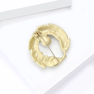 Detail view of gold feather brooch back showing high-quality safety pin and texture