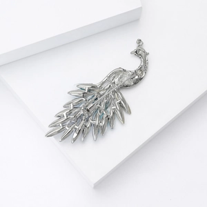 Close-up of silver peacock brooch featuring intricate feather design and rhinestone accents