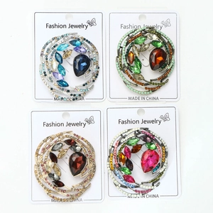 Detail of four crystal bird nest brooches with large teardrop gems in various colors