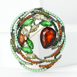 Detailed macro view of vintage bird nest brooch with colorful crystals and ruby red stone