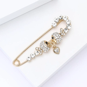 Detail of gold alloy fish brooch with white rhinestones and heart pendant on white steps