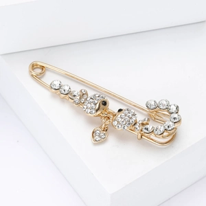 Close-up of gold safety pin brooch with sparkling crystals and a cute heart pendant