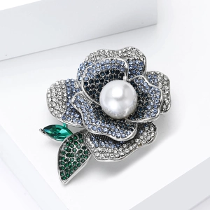 Macro shot of peony flower brooch with blue rhinestones and a large white faux pearl