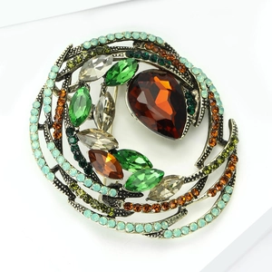 Macro detail of vintage bird nest brooch with amber crystal and multi-color rhinestones