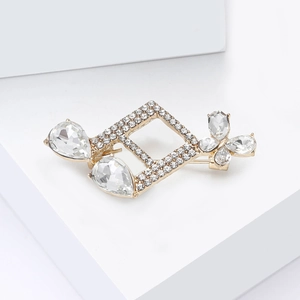 Détail d'une broche dorée élégante avec strass et cristaux en poire sur cubes blancs