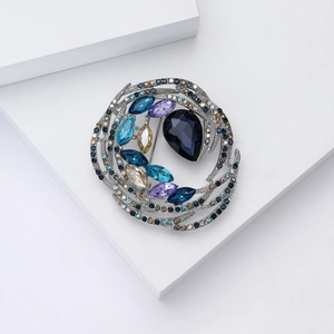 Detailed view of nest-shaped crystal brooch with blue waterdrop stone and silver setting